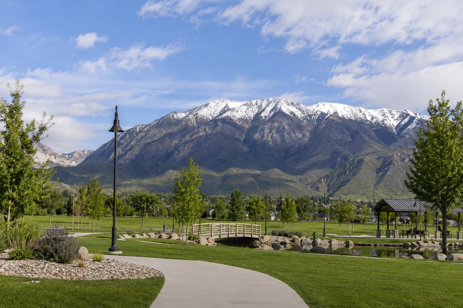 Snow-capped mountains above a green park in Orem, Utah