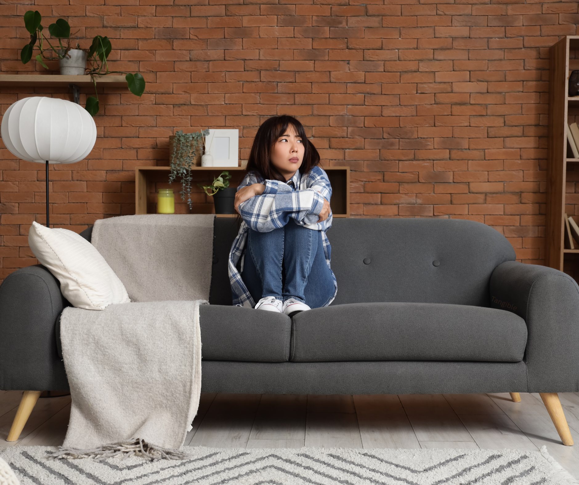 Asian Woman sits on couch seeking therapy for depression at Tangible Therapy
